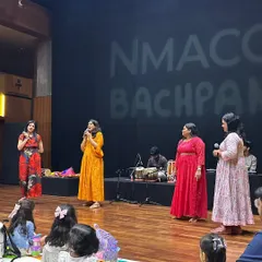 On stage at NMACC Bachpan, we are joined by our team of musicians to present a rich tapestry of Indian folk music. The children are seated on mats, ready for an immersive session of sound and culture.