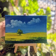 This peaceful field scene on its easel is ready to bring a bit of calm to any space. It’s a reminder of the simple beauty found in nature, captured with oil paints.