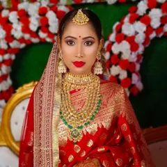 A direct portrait of the Bengali bride, showcasing the iconic red bindi and intricate gold jewellery.