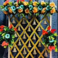 For a touch of traditional artistry, I designed this unique backdrop using a golden jaali or lattice frame. Each opening is decorated with a delicate golden bell, and the frame is topped with a colorful arrangement of artificial flowers.