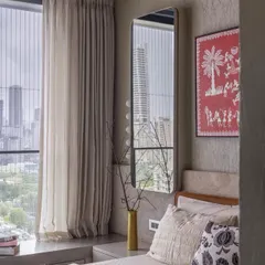 A bedroom with a view of the Mumbai skyline, where soft, neutral textiles and a piece of traditional Warli art create a space that is both urban and culturally rooted.