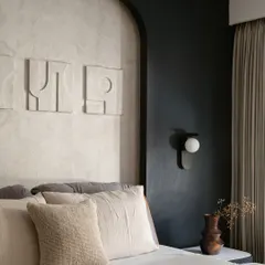 In this bedroom, I explored the power of a monochrome palette to create a space that is both youthful and sophisticated. The design is built on layers of texture, from the lime-washed wall behind the bed to the abstract art and soft linens. Every detail, including the modern wall sconce and custom headboard, was chosen to make the compact room feel intentional and full of character.