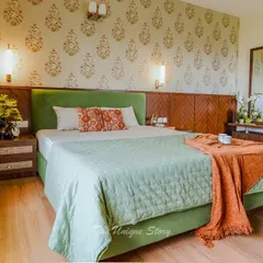 A master bedroom renovation that blends old and new. We designed a new green velvet upholstered bed and paired it with a traditional Indian block-print style wallpaper. The custom wooden headboard and nightstands add warmth and a touch of heritage.