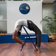 Using a chair for a deep backbend like this variation of Urdhva Dhanurasana provides stability and allows the practitioner to focus on opening the thoracic spine. It's a perfect example of how props can transform and deepen your asana practice.