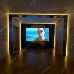 Our designs seamlessly blend with your home's interior. This theater features a clean, modern aesthetic with herringbone wood flooring and architectural LED lighting that frames the viewing area, housing a high-performance audio-visual system.