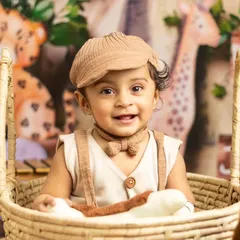 A happy little explorer in our 'Into the Wild' jungle-themed setup. We use props like baskets and stuffed animals to create an immersive scene.