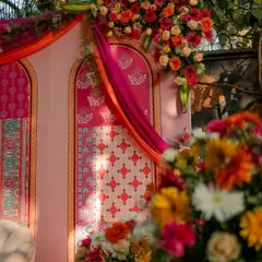 The interplay of sunlight and shadow highlights the intricate details of the floral bouquets and the printed backdrop, creating a warm and inviting atmosphere.