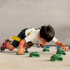 This young climber tackles a horizontal traverse, a fun challenge that builds strength and technique without the fear of heights. It's a great starting point for our youngest adventurers.