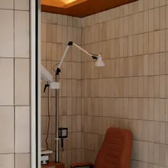 Even functional areas like the vision assessment room are designed with care, featuring the same warm material palette of neutral wall tiles and an arched ceiling to ensure a cohesive aesthetic throughout the store.