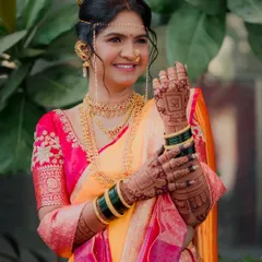 A beautiful portrait of a Maharashtrian bride proudly showing her intricate mehndi design. Her happy smile and traditional jewelry, including the mundavalya, complete the perfect bridal look.
