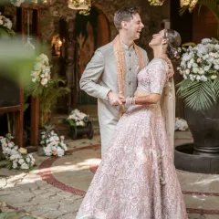 A moment of pure, unscripted laughter between the bride and groom in a beautiful courtyard setting on their wedding day.