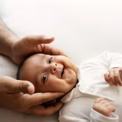 A happy, gurgling smile from this sweet newborn as dad gently holds his face. Capturing these early interactions is just priceless.