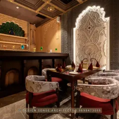 This corner shows how we balance different elements. A grand, backlit archway sits next to a bar area featuring a peacock motif, all tied together with traditional carved furniture and rich, warm lighting for a fine dining setting.