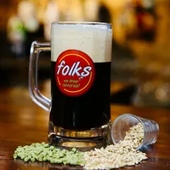 A full mug of a dark craft beer from Folks brewpub. The composition is clean and direct, with the blurred background of the bar adding authentic atmosphere.