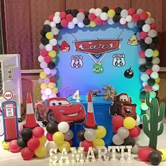 Ready, set, go! A high-energy 'Cars' themed birthday decoration for a 4th birthday. The setup includes a Lightning McQueen cutout, a balloon arch in the theme's colors, and Route 66 signs.