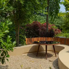 **Playfold, Ahmedabad:** The terrazzo bench is backed by a simple wooden fence, providing support and a warm, textural contrast. This area is perfect for family meals or small gatherings, seamlessly integrated into the garden.