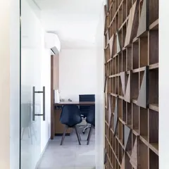 A view from the corridor into one of the consultation rooms. The glass partition allows light to flow through the space, while the wooden screen on the right adds warmth and texture.