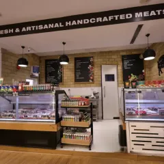 This dedicated section for fresh and artisanal meats uses a clean, deli-style design with subway tiles and clear signage. The refrigerated displays are integrated seamlessly, ensuring product freshness while maintaining a high-end butcher shop aesthetic.