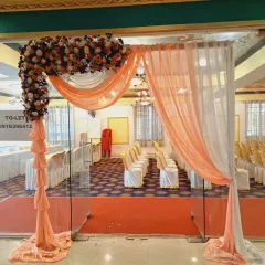 A simple and elegant entrance arch for a hall. I used a combination of peach and white drapes with a floral arrangement on the corner to create a welcoming passage for guests.