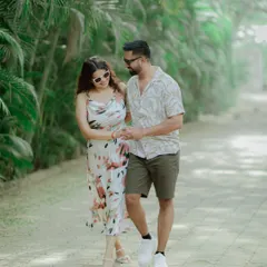 A couple in casual, summery outfits enjoys a walk through a path lined with palm trees. This image feels natural, relaxed, and perfect for a vacation-style shoot.