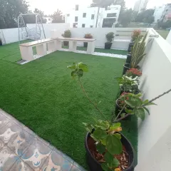 This terrace features artificial grass paired with built-in seating and a variety of potted plants. It shows how you can combine artificial turf with live plants for a beautiful effect.