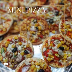 A close-up of our delicious mini pizzas, topped with corn, olives, and colorful peppers. These bite-sized treats are perfect for any party or event.