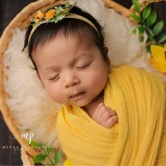 A close-up portrait of the baby in the basket, focusing on their sweet, sleeping face and the delicate floral headband.
