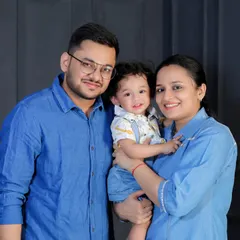 A beautiful family portrait with everyone dressed in shades of blue. The parents hold their toddler, creating a coordinated and loving image.