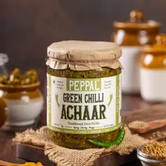 A rustic, moody shot of Peppal's Green Chilli Achaar, styled with whole spices and traditional pottery. This approach highlights the product's authentic, homemade quality.