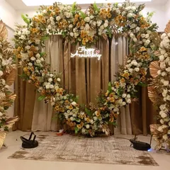 To celebrate a special anniversary, I created this grand heart-shaped arch completely covered in white and gold-toned flowers, with a custom neon sign and matching floral stands.