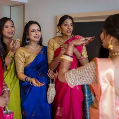 The bride gestures to her friends, sharing a laugh and showing off her final look. Their expressions are a mix of joy and emotion.