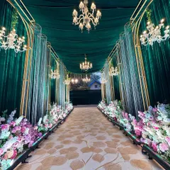 I design walkways that are an experience in themselves. Here, a path lined with lush florals and grand chandeliers guides guests through an emerald and gold archway, setting a tone of pure opulence.