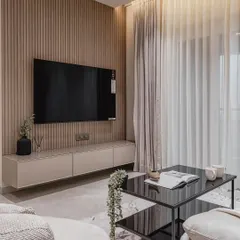 For this living room, we created a floating TV unit that serves as a sophisticated focal point. The design combines a European membrane finish with routed shutters, a fluted panel background, and a back-painted glass top for a clean, textured, and luxurious feel.