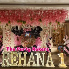A stunning Minnie Mouse-themed first birthday. The main stage features large marquee letters, a floral backdrop, and a black and pink balloon arrangement.