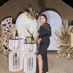 The birthday girl posing in front of her elegant boho-themed decor. The natural textures of the thatched roof and pampas grass complement her stylish look perfectly.