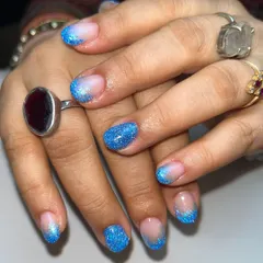 Dipped in ocean dreams. These glittery blue nails feature a beautiful ombré effect, fading from a natural base to sparkling blue reflective glitter at the tips.