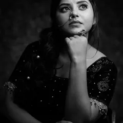 The same subject, captured in a classic black and white studio portrait. This style strips away color to focus on expression, form, and the texture of her embellished blouse, creating a timeless and dramatic headshot.