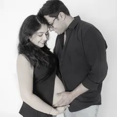 An intimate and tender black and white portrait. This close-up shot captures the couple forehead-to-forehead, both gently holding the baby bump, full of love and connection.