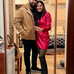 A mirror selfie capturing a perfect New Year's Eve look. The hot pink satin dress paired with sheer tights and chunky thigh-high boots is bold, festive, and ready for a party.