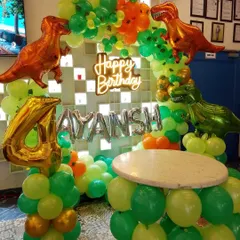 A dinosaur-themed birthday is always a hit with the kids. This setup includes a custom balloon arch with T-Rex foil balloons, a neon "Happy Birthday" sign, and a matching balloon-wrapped table for the cake.