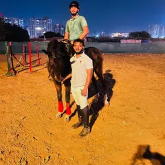 A rider and trainer stand with their horse after a successful evening training session.
