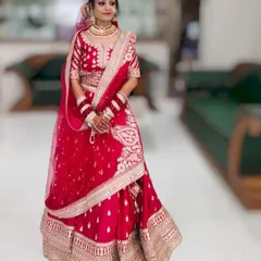 A beautiful full-length shot of a bride in her red wedding lehenga. The makeup is balanced to enhance her features without being too heavy, ensuring she looks her best.