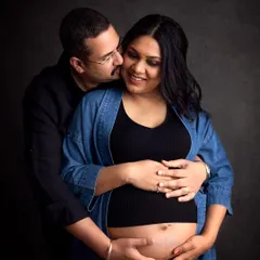 Candid moments are my favorite! This couple's joy is so real in this moody, dark-background portrait from their studio maternity shoot.