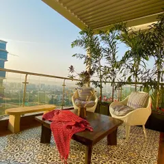 A closer look at the seating area, where we laid beautiful patterned tiles to define the space. The combination of wicker chairs, a solid wood coffee table, and tall palms for privacy makes this the perfect spot for conversations.