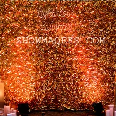A glamorous photo wall made of shimmering gold foil and a neon 'Light Love Laughter' sign, perfect for a festive party.