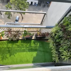 An aerial view of a complete balcony makeover. We combined a vertical garden for maximum greenery in a small footprint, planters along the railing, and a neat artificial lawn to create a comprehensive green escape with a city view.