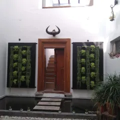 In this unique villa courtyard, we installed two symmetrical vertical gardens to frame a doorway, creating a grand and natural entrance. The design works with the indoor water feature and stone path for a cohesive, tranquil feel.