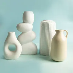 A collection of modern, minimalist white ceramic vases in various shapes and textures, shot against a soft blue background for a serene home decor look.