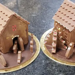 Our chocolate Christmas huts are a festive delight. This image shows two of our detailed creations, complete with chocolate trees and fences, ready for a holiday celebration.