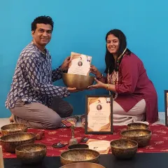 The path of a sound healer begins with dedication and an open heart. Here, a student receives her Sound Healing Teacher Training certificate, surrounded by the Tibetan singing bowls that are central to this deeply vibrational and healing practice.